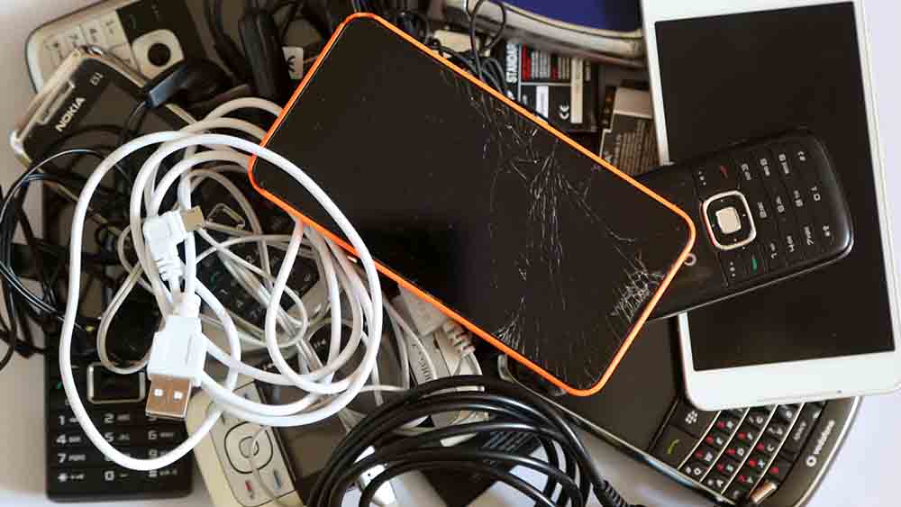 Alte, kaputte Handys und Kabel liegen nebeneinander