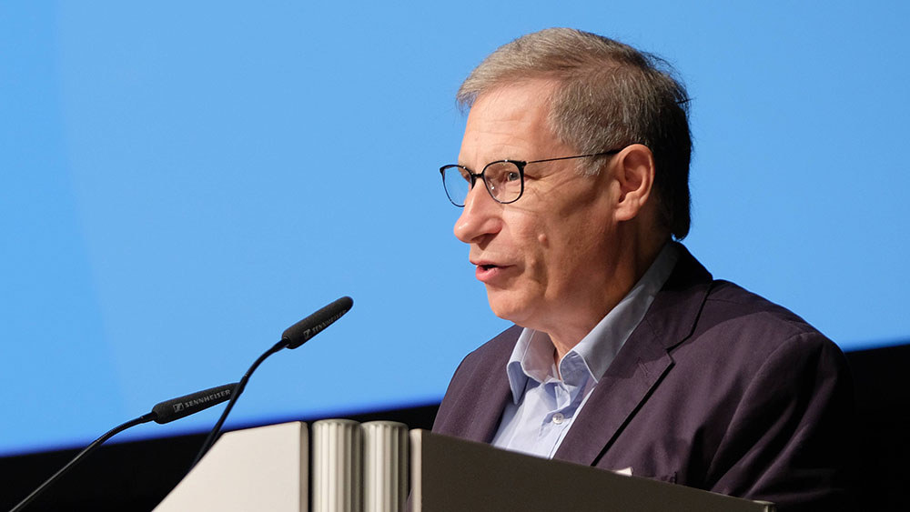 Mann im dunklen Anzug und blauen steht an einem Rednerpult