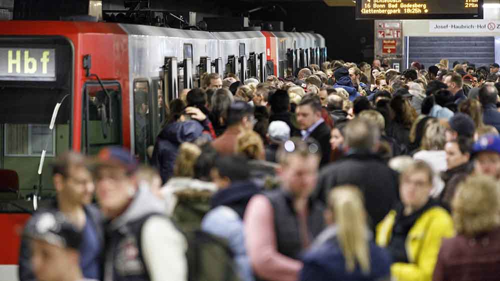 Menschen drängeln sich vor einer U-Bahn an einer vollen Haltestelle