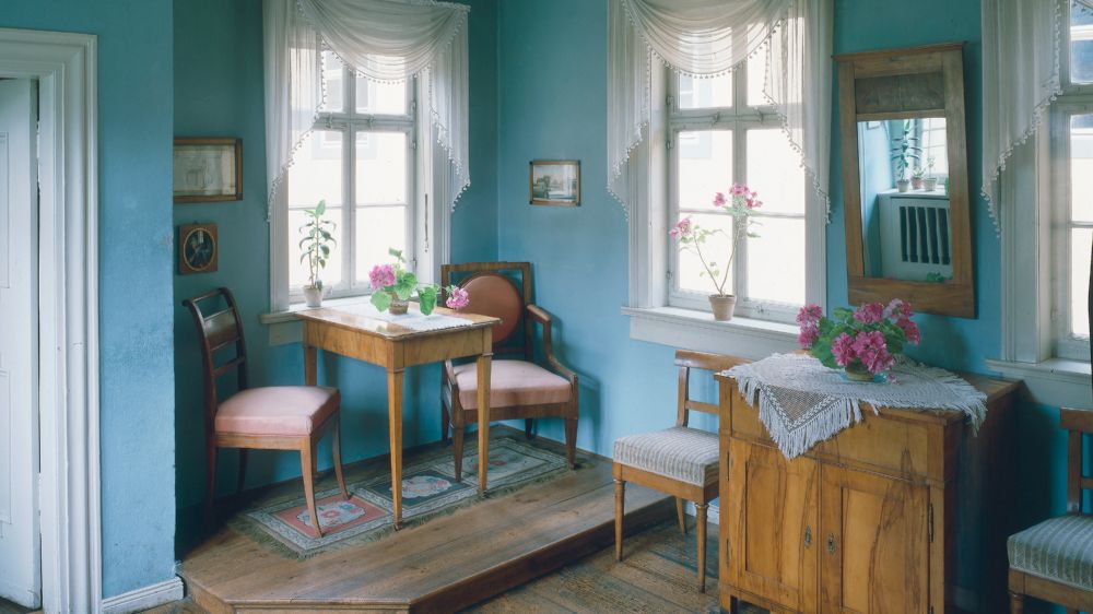 Ein kleines Wohnzimmer mit Holzboden, Kommode und einen kleinen Tisch.