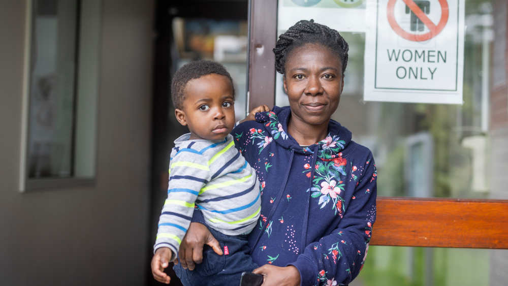 Afrikanische Frau mit Kind auf dem Arm schaut in die Kamera