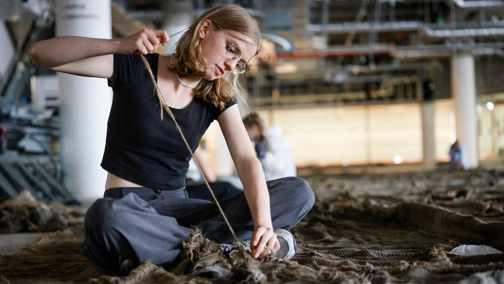 Schülerin aus Osnabrück näht Bahnen aus Jute zusammen