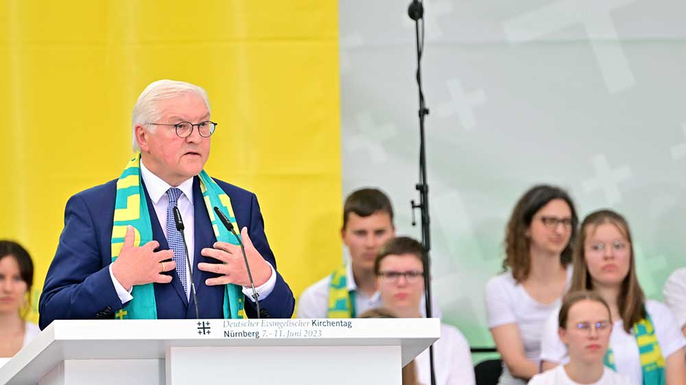Steinmeier mit Kirchentagsschal auf einem Podium