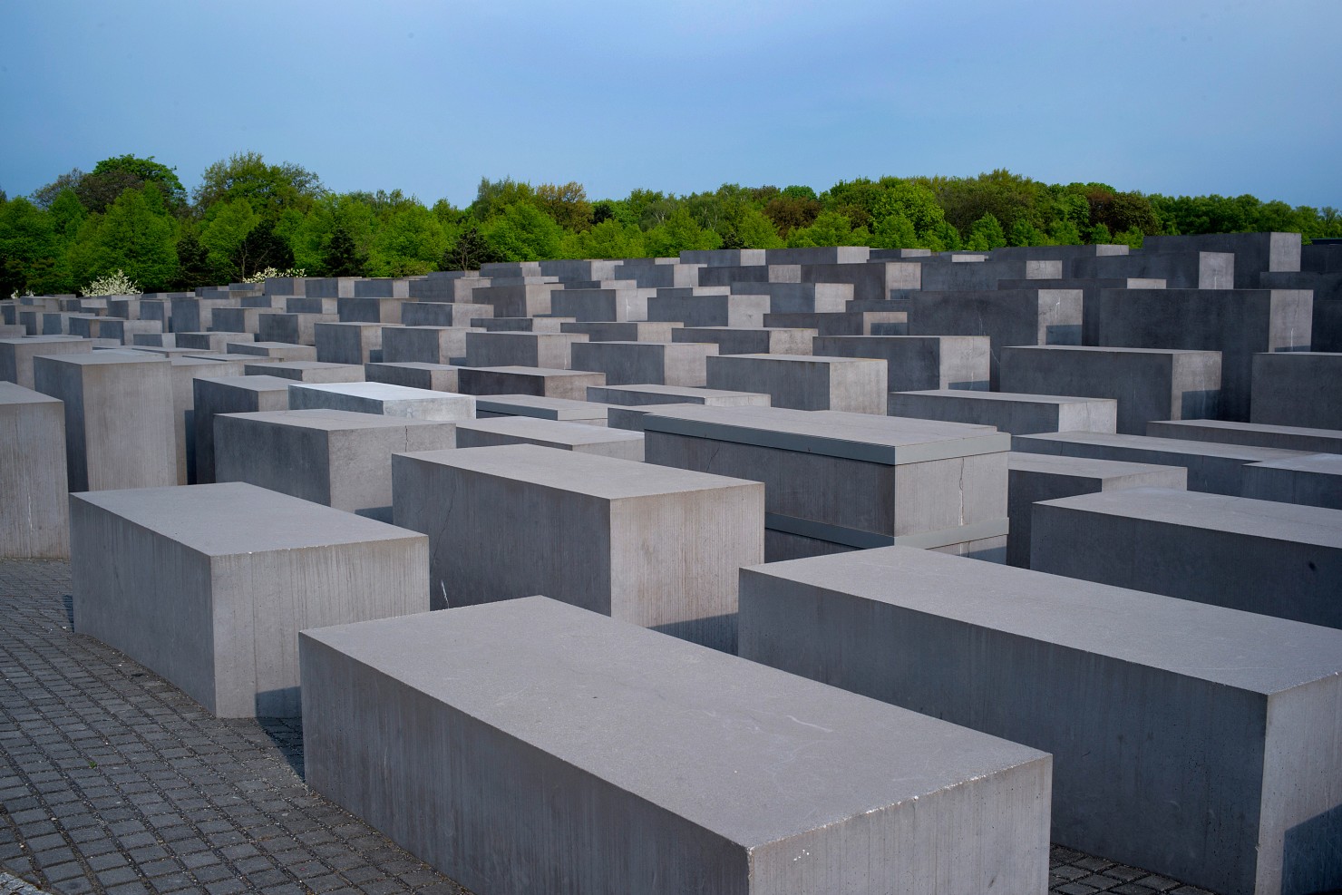 Im Bildausschnitt sind die unterschiedlich hohen Stelen des Holocaust Mahnmals in Berlin zu sehen. Aus dieser Perspektive kann man sehen, dass sich aus den einzelnen Steinblocken eine Wellenbewegung ergeben zu scheint.