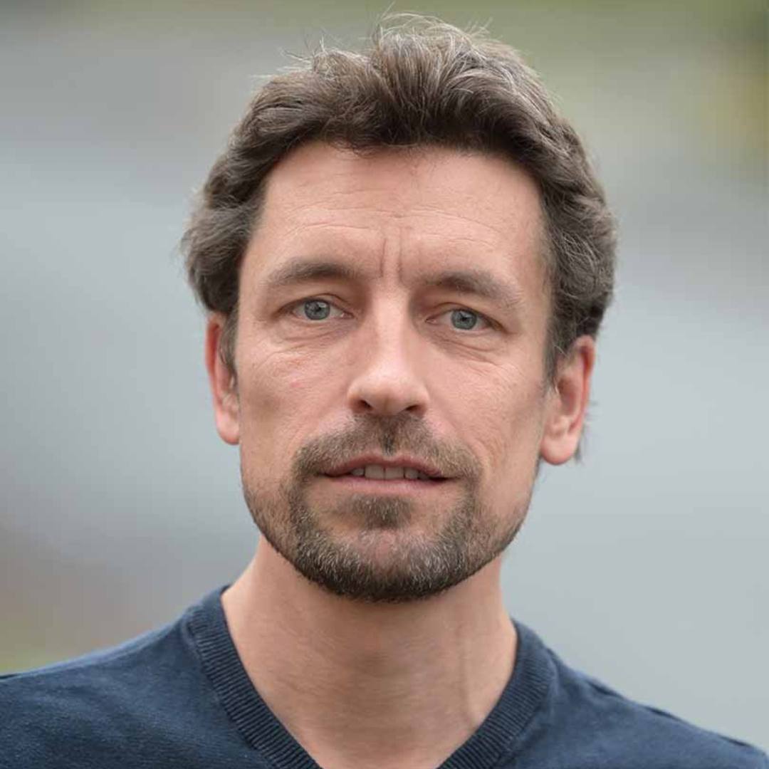 Porträt: Mittelalter Mann mit dunkelblonden Haaren und grauem Pulli