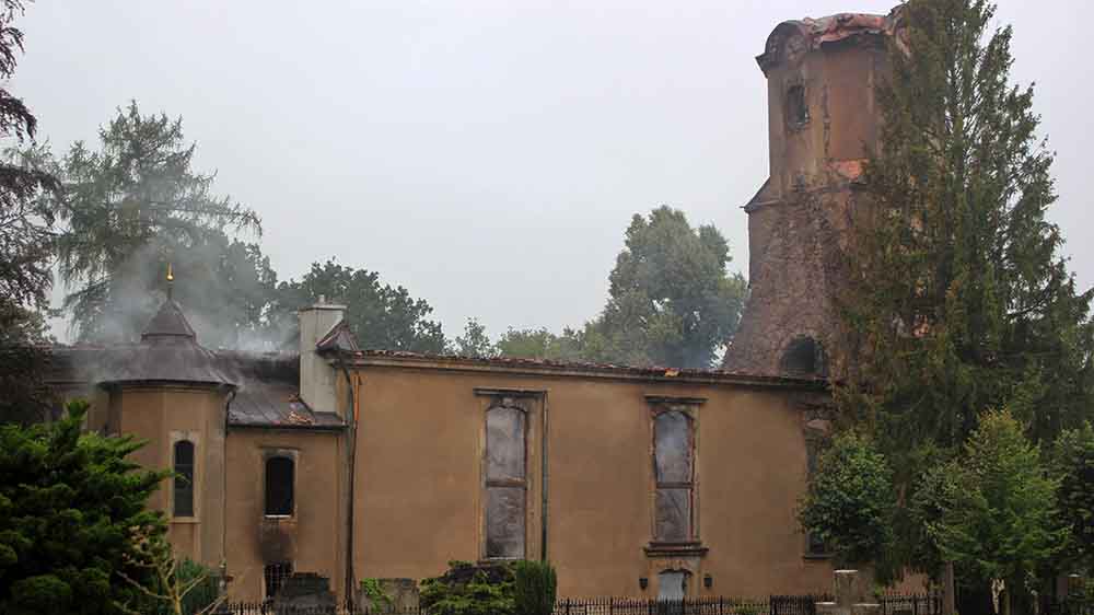 Mauern einer zerstörten Kirche, aus denen Rauch aufsteigt