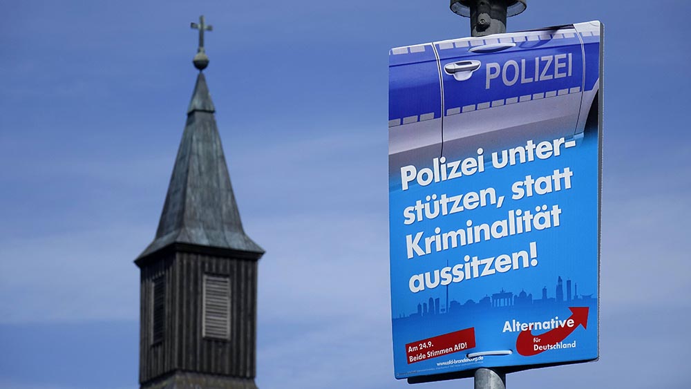 Vor einem Kirchturm hängt ein Plakat der AfD