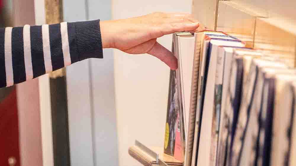 Nahaufnahme einer Hand, die zu einem Bücherregal greift