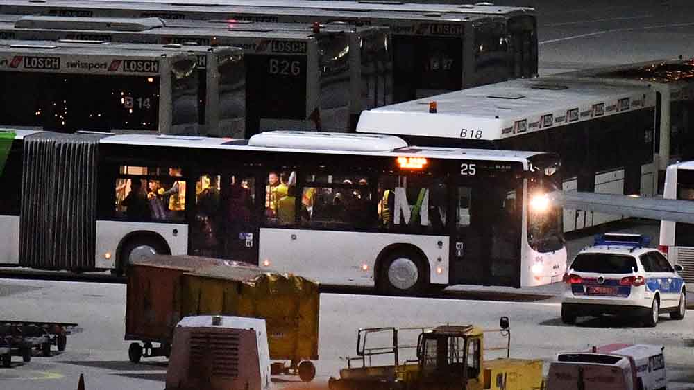 Bus mit vielen Menschen steht auf dem Rollfeld eines Flughafens