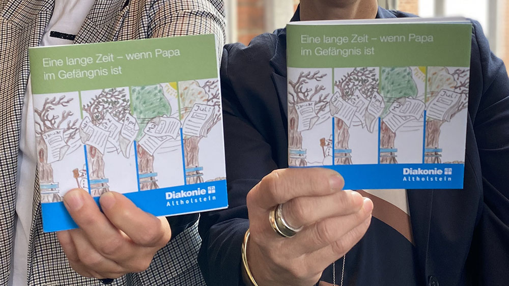 Zwei Hände halten zwei Bücher in die Kamera