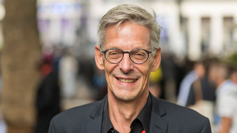 Porträtfoto mittelalter Mann mit grauen Haaren und Brille und schwarzem Blazer