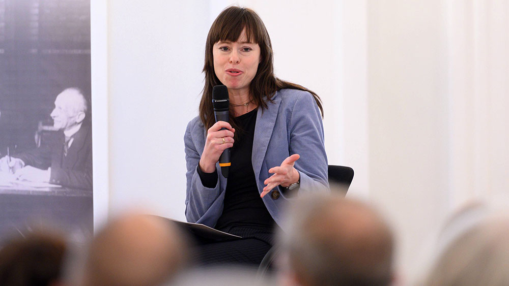 Frau im lila Blazer auf einem Podium