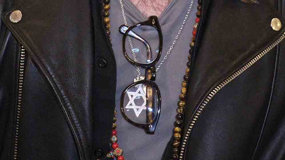 Nahaufnahme einer Kette mit einem Davidstern, die ein Mann um den Hals trägt. Das Gesicht des Mannes ist nicht zu erkennen