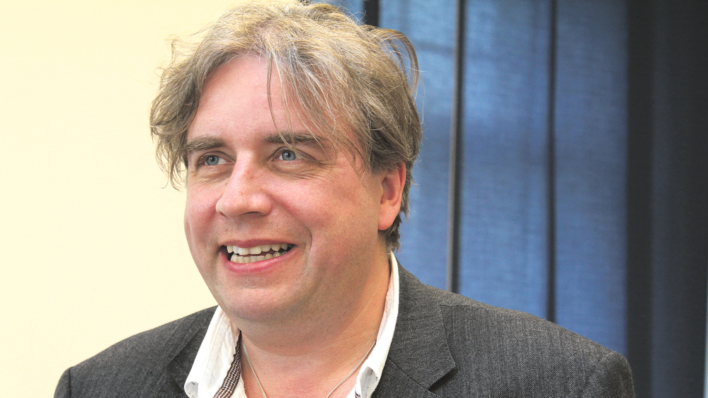 Mann mit grauen Haaren und schwarzem Anzug schaut in die Kamera