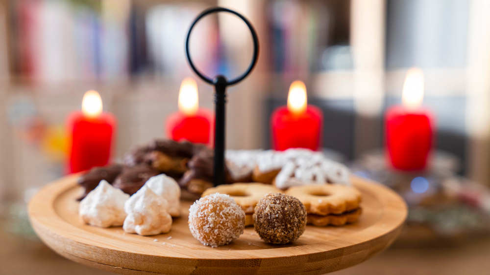 Weihnachtsplätzchen auf einem Holzbrett, im Hintergrund brennen vier rote Kerzen