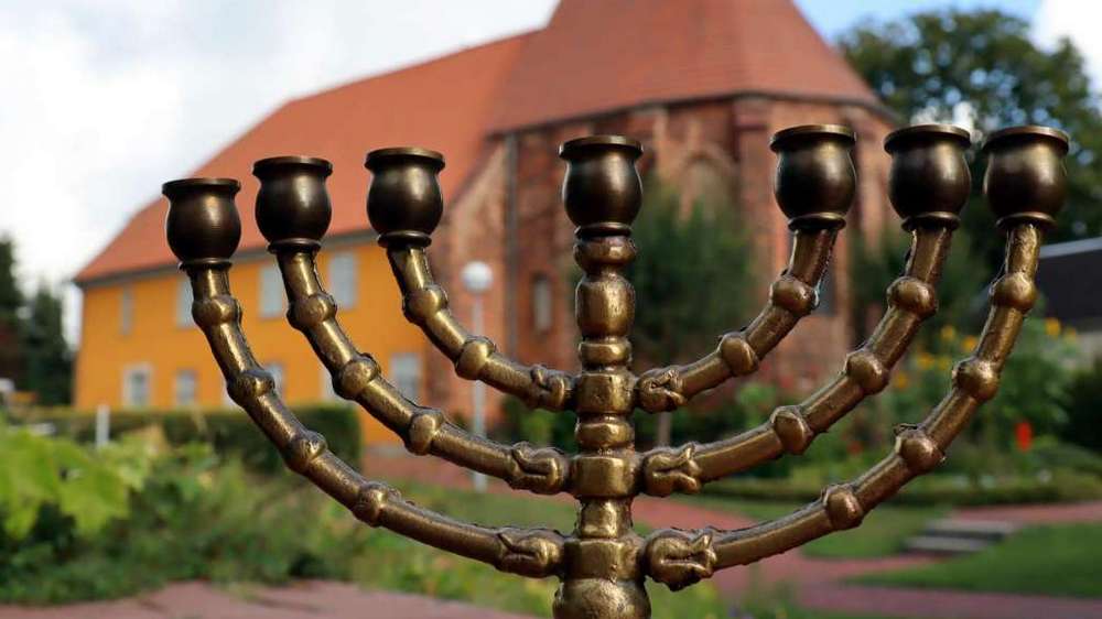 ein chanukka-Leuchter steht im Vordergrund, dahinter ein Haus