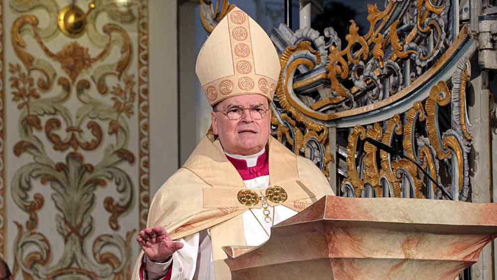 Mann im Talar steht auf einer Kanzel und redet