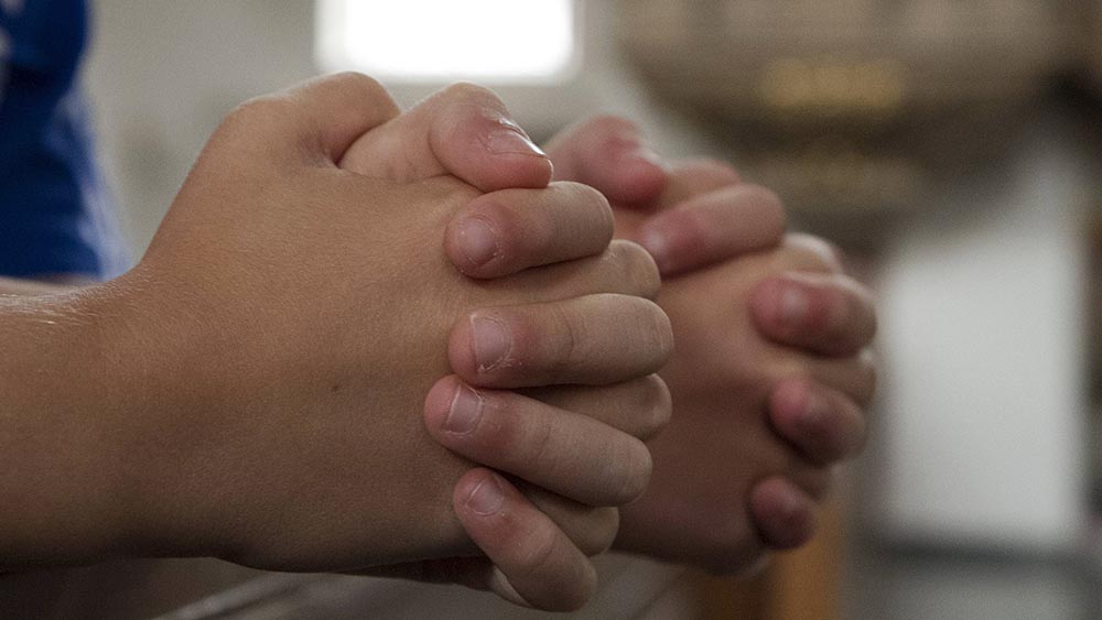 Nahaufnahme von zwei Händenpaaren, die zum Gebet gefaltet sind