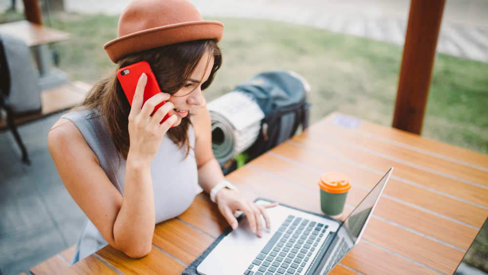 Frau mit Laptop und Handy am Tisch