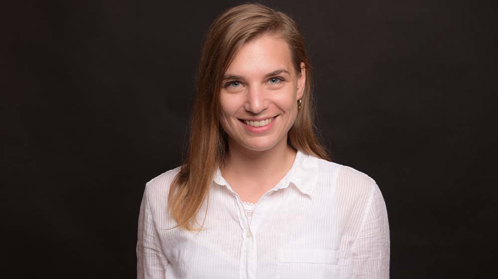 Junge Frau mit dunkelblonden langen Haaren und einer weißen Bluse