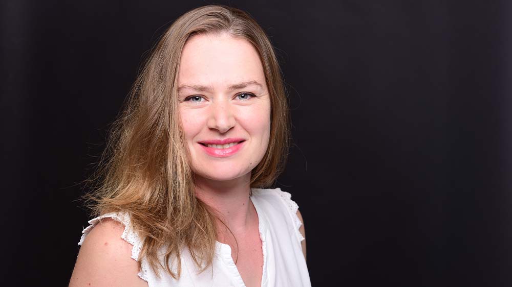 Junge Frau mit mittelblonden, langen Haaren und weißem Top