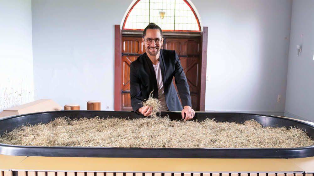 Mann steht hinter einem Sarg aus Heu und Stroh