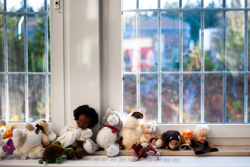 Kuscheltiere vor einem vergitterten Fenster