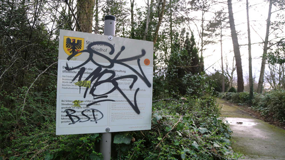 Sprayer haben ein Hinweisschild der Friedhofsverwaltung bis zur Unleserlichkeit besprüht