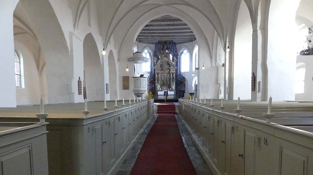 Blick in das ein leeres Kirchenschiff mit viel weißem Holz