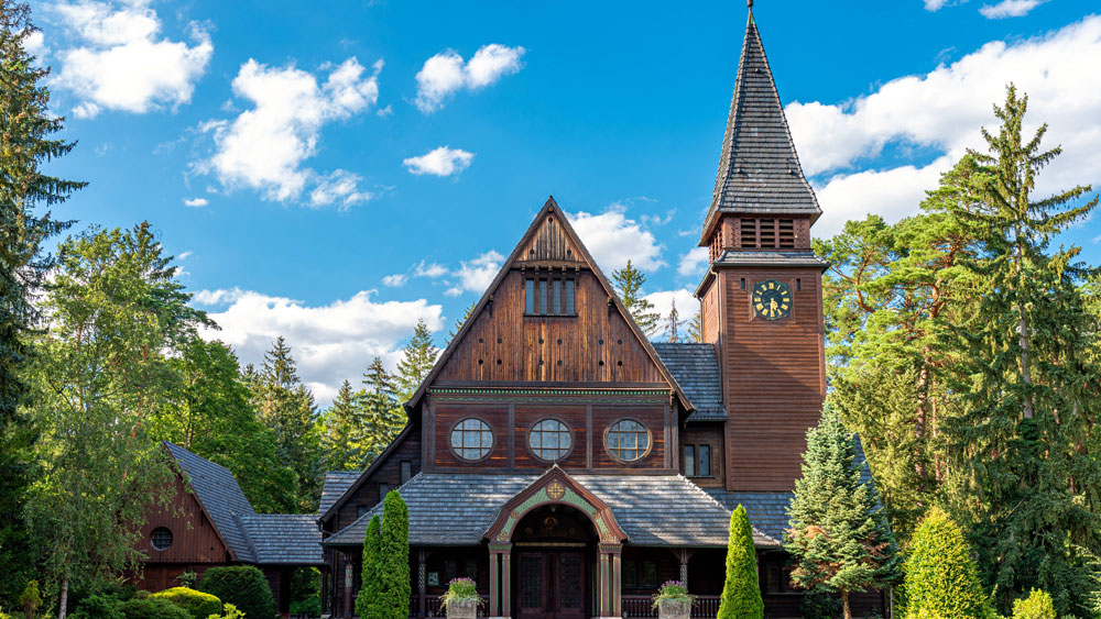 Kirche aus Holz mit Turm. Dahinter blauer Himmel.