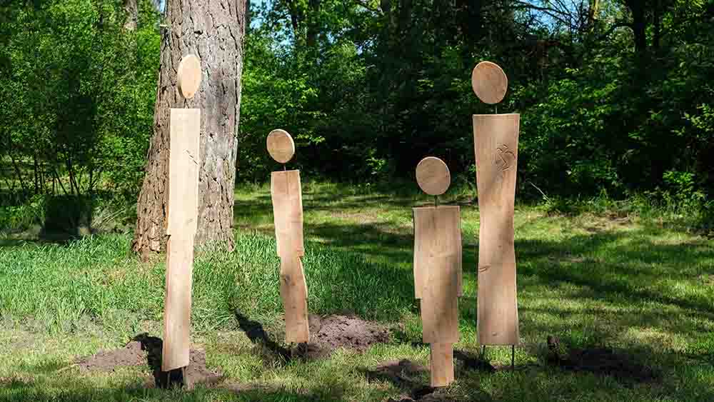 Vier lange Holzstäbe mit Kreis auf dem Kopf in einer Lichtung