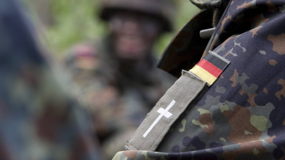 Am Arm eines Soldaten klebt unter der Deutschland-Fahne ein Kreuz