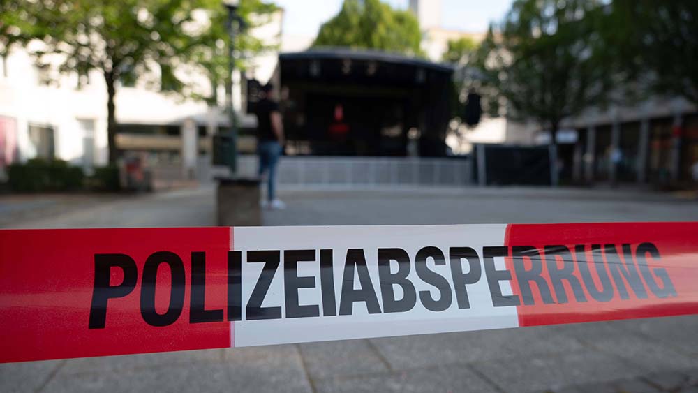 Vor einer Bühne weht ein rot-weißes Flatterband mit der Aufschrift "Polizeiabsperrung"
