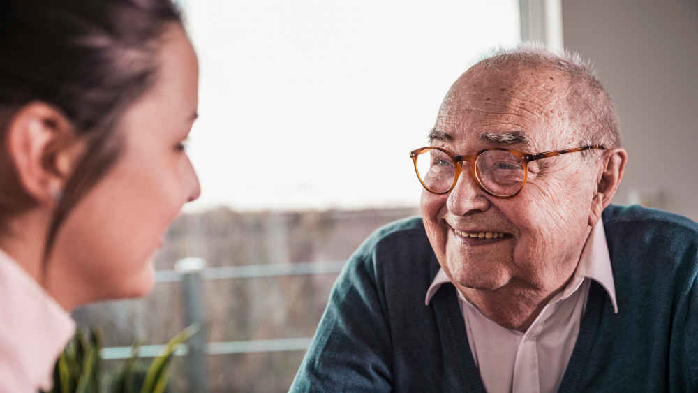 Alter Mann lächelt junge Frau an