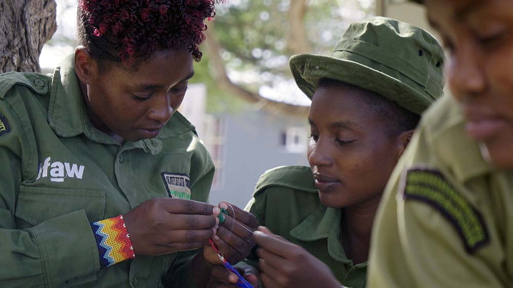 Zwei Frauen in grünen Uniformen schauen auf einen kleinen Gegenstand, den eine der Frauen in der Hand hält