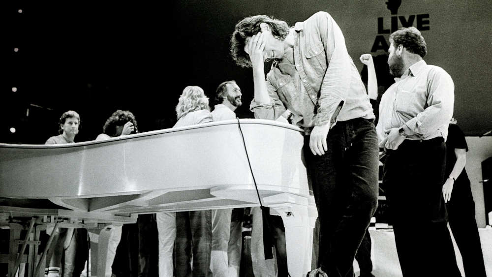 Schwarz-weiß-Bild von Männern, die sich um einen Flügel versammeln