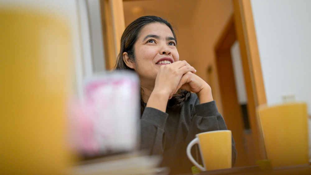 Frau sitzt am Tisch mit Kaffeebecher