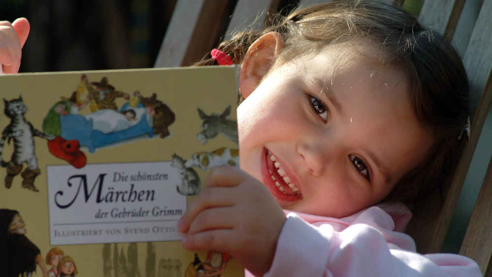 Lächelndes Kind mit Märchenbuch in den Händen