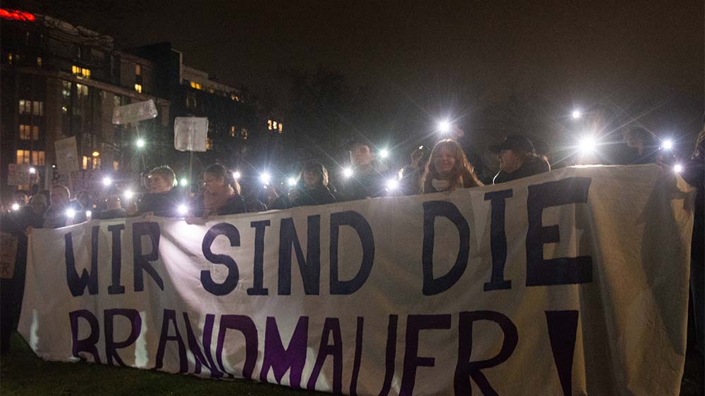 Demo-Teilnehmende halten ein Schild mit den Worten "Wir sind die Brandmauer"