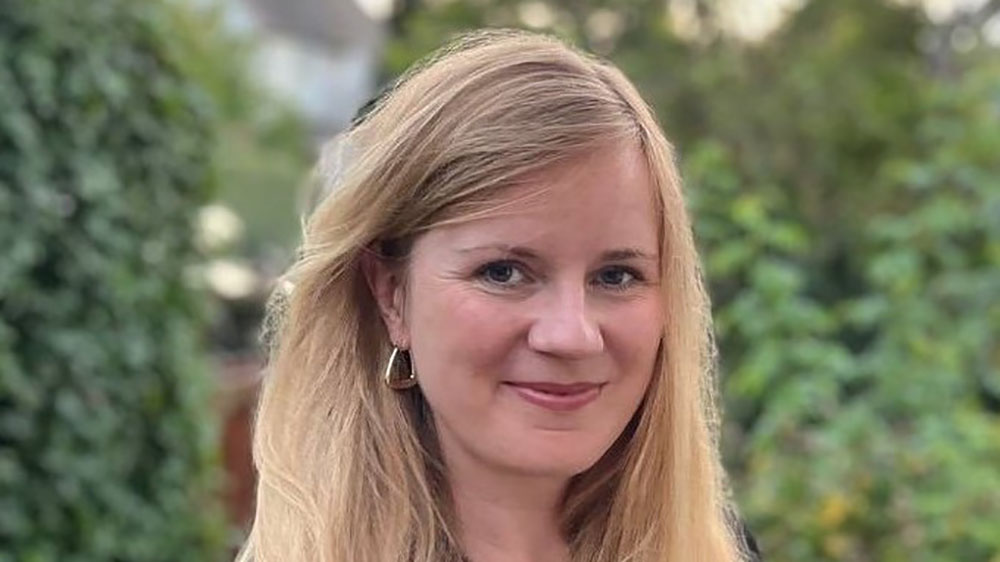 Frau steht vor Büschen.