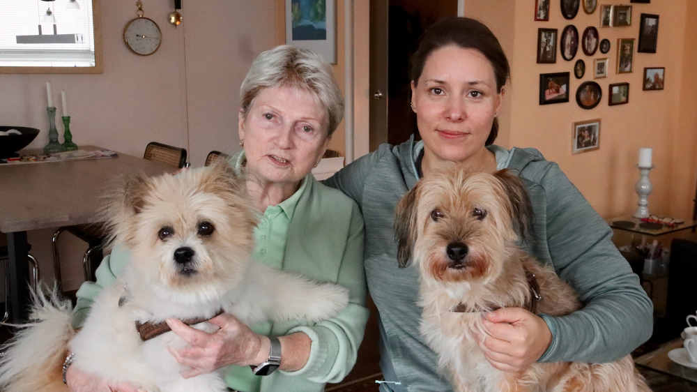 Zwei Frauen sitzen mit Hunden auf dem Arm