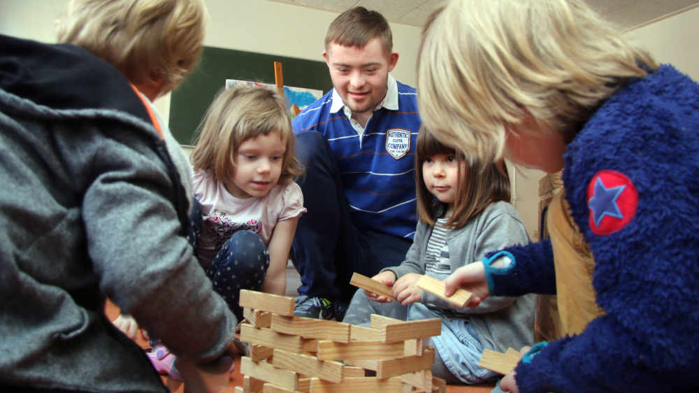Junger Mann in Kindergruppe einer Kita
