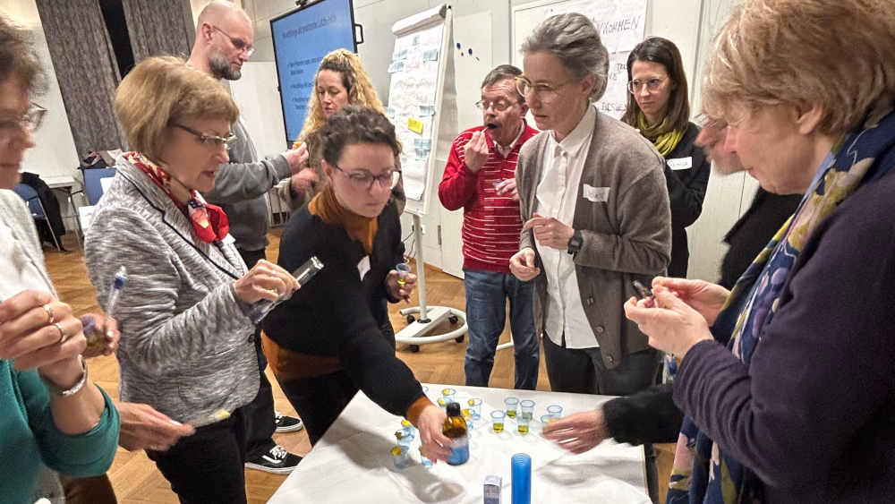 Kursteilnehmer stehen um einen Tisch mit Hilfsmitteln