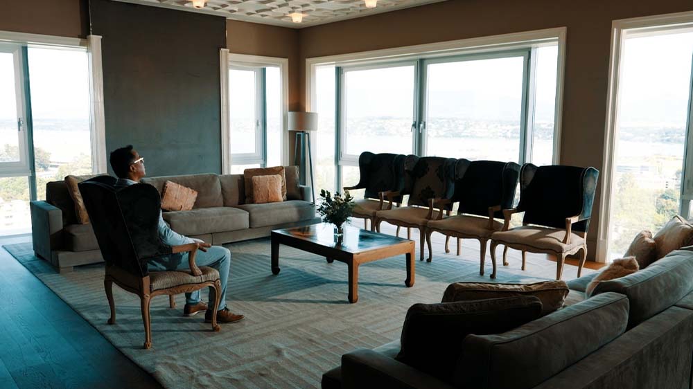 Ein Mann sitzt auf einem Sessel in einem edlem Hotelzimmer und schaut aus dem Fenster