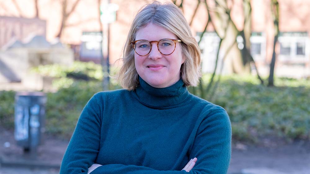 Mittelalte Frau mit mittellangen, blonden Haaren und einer modernen, hellbraunen Brille