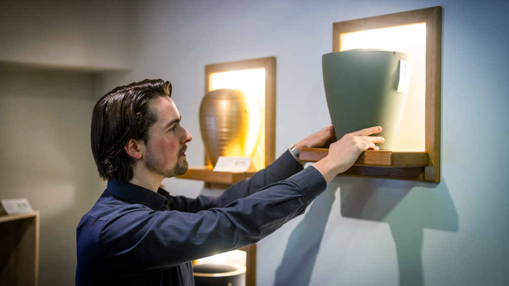 Bestatter stellt Urne in ein Regal