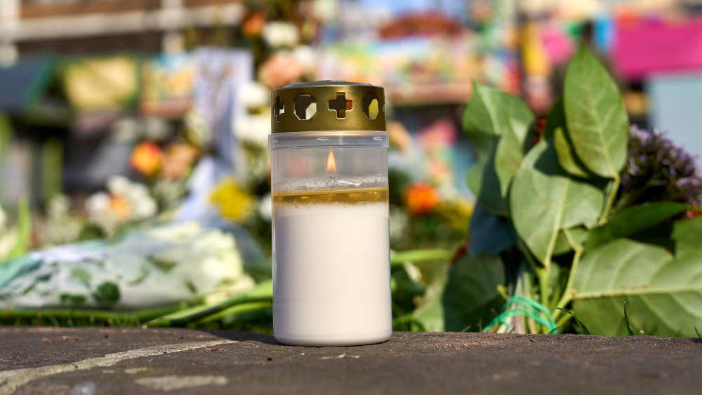 brenndene Trauerkerze vor Blumen