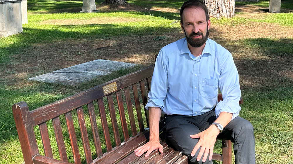Mann im blauen Hemd sitzt auf einer Bank im Park