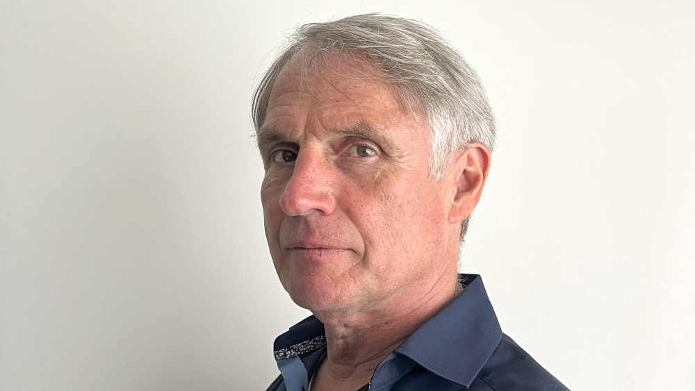 Mann mit grauen Haaren schaut seitlich in die Kamera