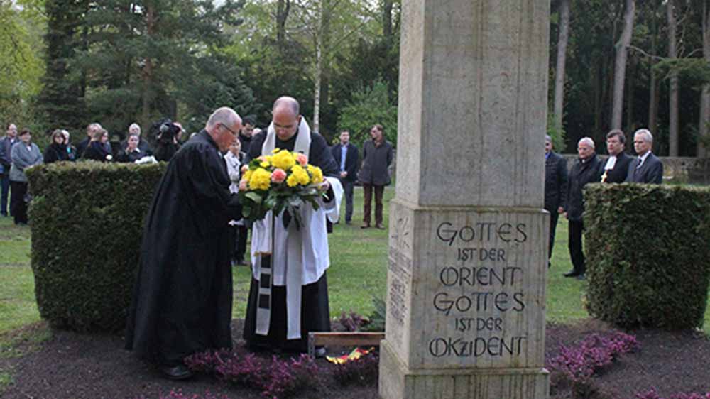 Ein katholischer und ein evangelischer Priester legen in Demmin auf dem Friedhof einen Kranz nieder am Gedenkstein für die Verstorbenen von 1945.